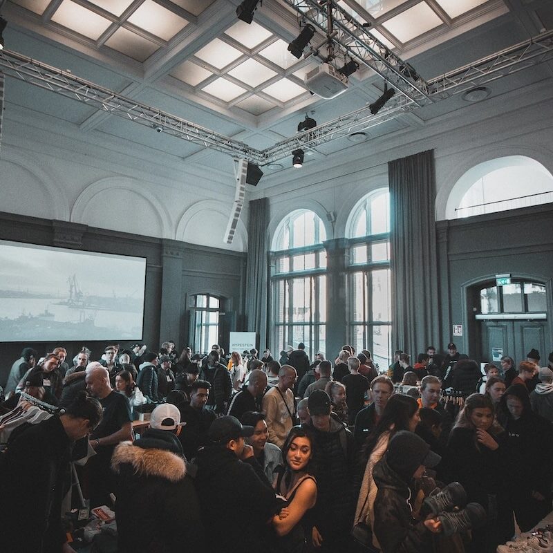 Image shows a group of people attending a marketing event. The people are gathered in front of a large screen