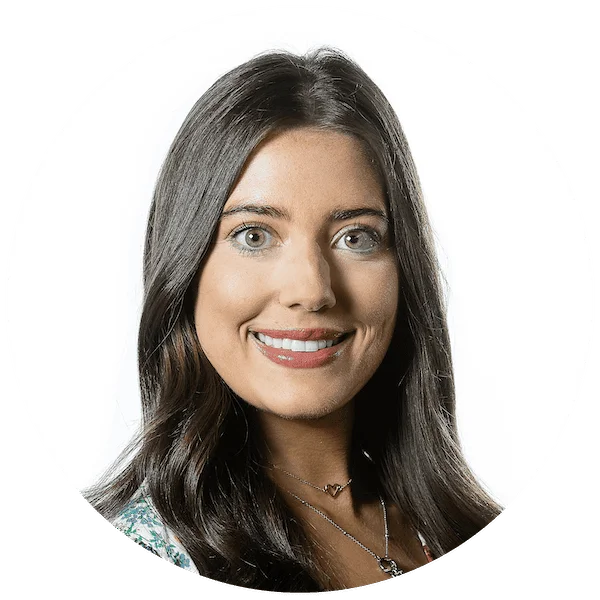 Professional headshot of a smiling woman with long dark hair, wearing a patterned top and layered necklaces.