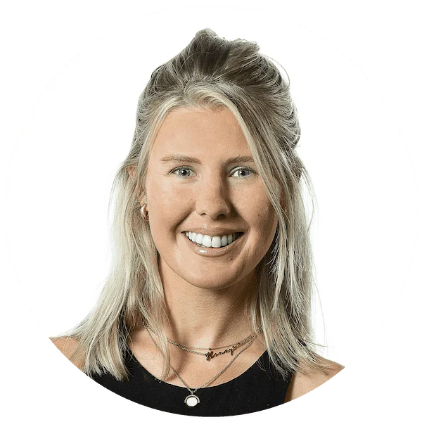 Headshot of a smiling woman with blonde hair wearing layered necklaces and a black top, set against a white background.