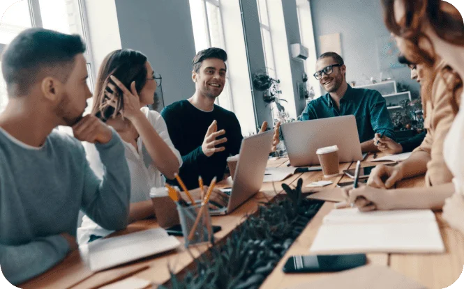 Team of colleagues having an engaging discussion around a table with laptops during a business meeting.