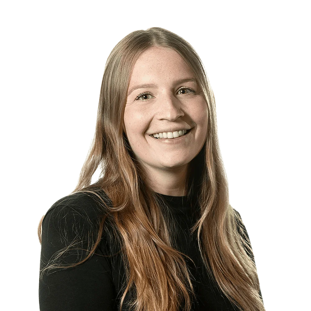 Professional headshot of a smiling woman with long brown hair, wearing a black top.