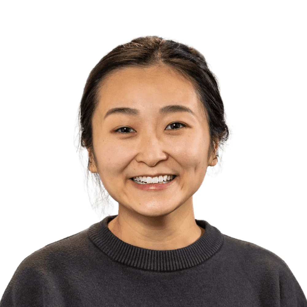 Smiling woman with dark hair pulled back, wearing a charcoal gray sweater, headshot against a white background.