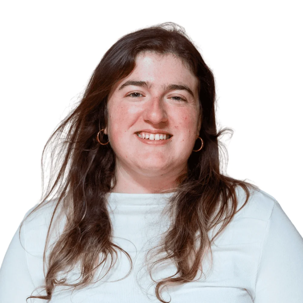 Smiling woman with long brown hair and gold hoop earrings wearing a white top, studio headshot portrait.
