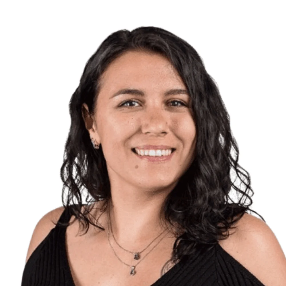 Smiling woman with long dark wavy hair wearing a black top and layered necklaces, studio headshot portrait.