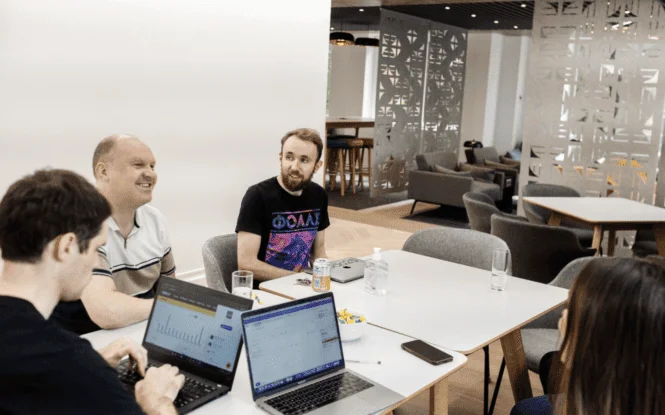 Team conducting user testing session around laptops in a modern office meeting space.